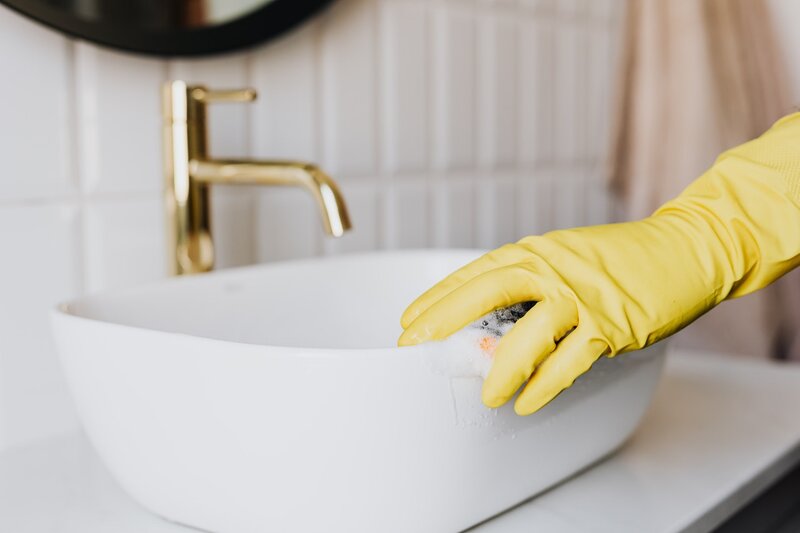 Persona limpiando un lavabo como parte de su rutina de limpieza