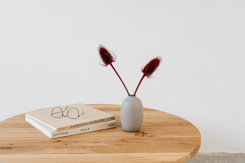Un jarrón y dos libros sobre una mesa de madera. Adaptar minimalismo a la vida real